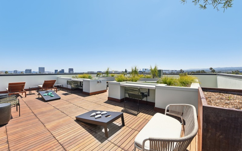 a patio with a couch, cornhole and chairs
