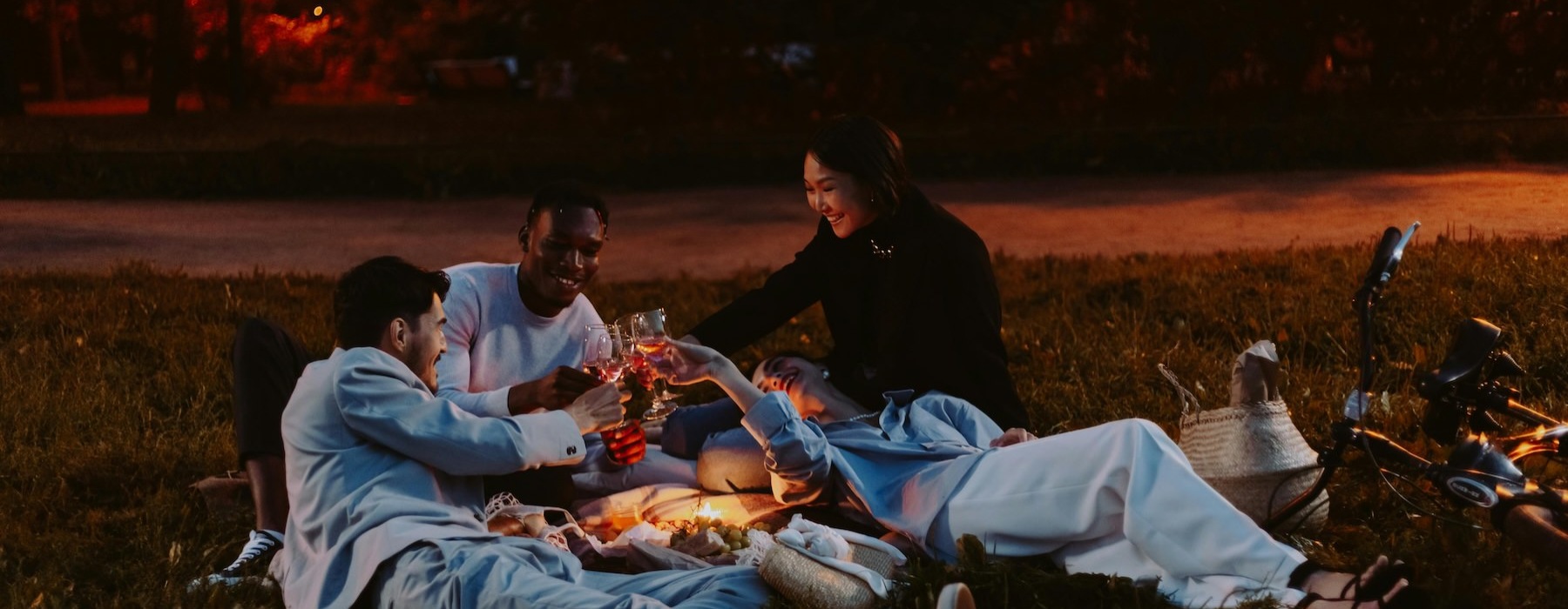 a group of people sitting on a blanket in a grassy area